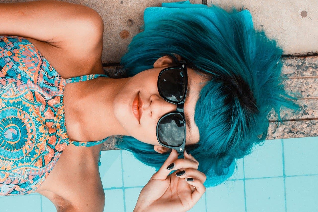 Kobieta w okularach przeciwsłonecznych z niebieskimi włosami